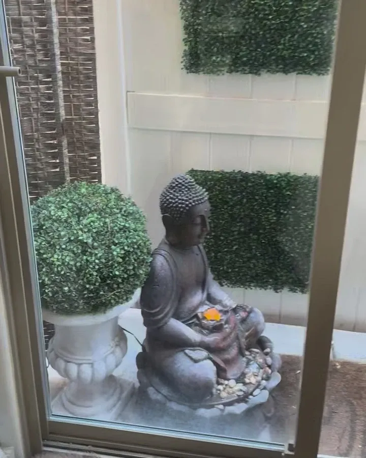 A Buddha statue and greenery seen through the glass door of Jo's treatment room