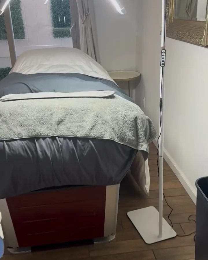 Jo's treatment room, with a made-up facial bed and a tall standing lamp beside it